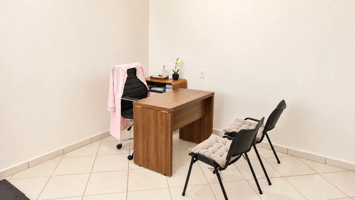 Área de atendimento com mesa de madeira e cadeiras para conversa.